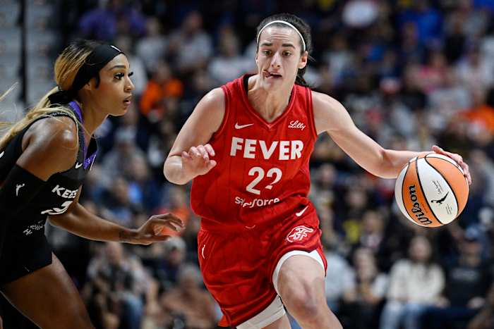 Indiana Fever-bewaker Caitlin Clark (22) rijdt naar de basket terwijl Connecticut Sun-bewaker DiJonai Carrington verdedigt tijdens een eerste ronde WNBA basketbal playoff-wedstrijd, woensdag 25 september 2024, in Uncasville, Conn. (AP Photo/Jessica Hill)
