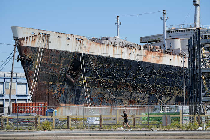 BESTAND - Een persoon rent langs de SS United States, afgemeerd aan de Delaware River in Philadelphia, 4 september 2024. (AP Photo/Matt Rourke, File)