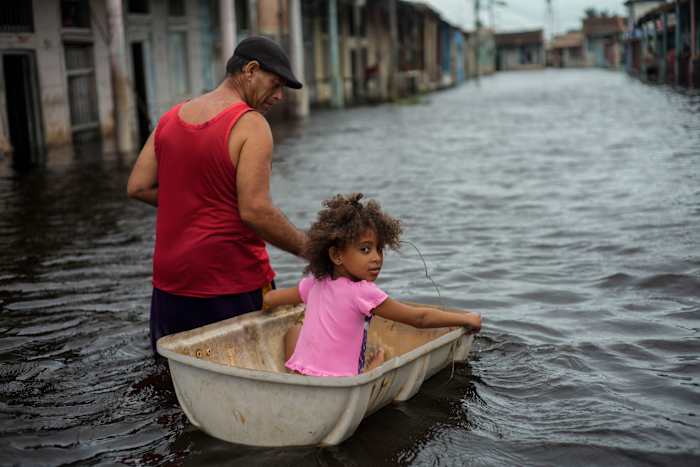 BESTAND - Jesus Hernandez begeleidt zijn kleindochter Angelina via een container door een straat die onder water kwam te staan ​​tijdens de orkaan Helene, in Batabano, provincie Mayabeque, Cuba, 26 september 2024. (AP Photo/Ramon Espinosa, File)