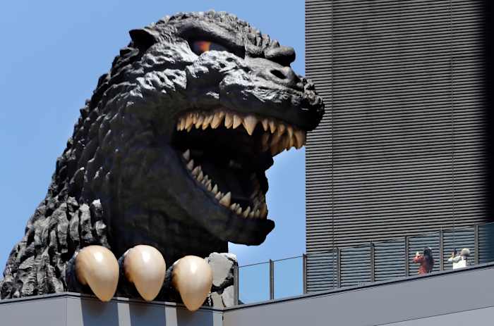 BESTAND - Mensen maken een foto van Godzilla's hoofd in het Shinjyuku Toho-gebouw in het Kabukicho-district in Tokio, 30 juli 2016. (AP Photo/Koji Sasahara, File)