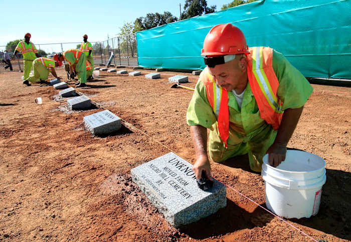 BESTAND - Steven Abujen, een Californische gevangene bij de Prison Industry Authority, maakt op 18 oktober 2011 een van de nieuw geïnstalleerde grafstenen schoon op de Mormon Island Relocation Cemetery, nabij Folsom, Californië. (AP Photo/Rich Pedroncelli, File )