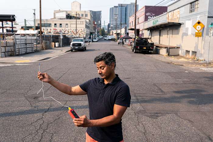 BESTAND - Vivek Shandas, hoogleraar klimaatadaptatie aan de Portland State University, doet een temperatuurmeting van bijna 106 graden in het centrum van Portland, Oregon, 12 augustus 2021. (AP Photo/Nathan Howard, File)
