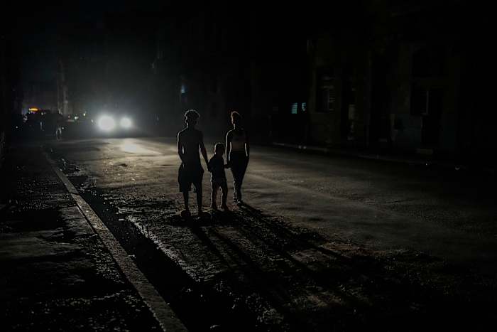BESTAND – Bewoners worden verlicht door de koplampen van een auto tijdens een stroomstoring nadat een grote elektriciteitscentrale uitviel in Havana, Cuba, 18 oktober 2024. (AP Photo/Ramon Espinosa, File)