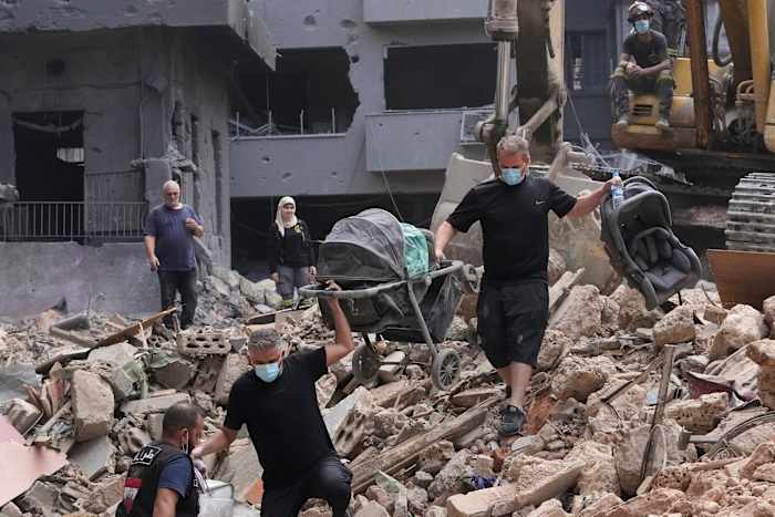 Bewoners van een gebouw dat beschadigd is door een Israëlische luchtaanval keren terug om de bezittingen van hun familie op te halen op de plaats van de Israëlische luchtaanval van donderdag in Beiroet, Libanon, zaterdag 12 oktober 2024. (AP Photo/Hassan Ammar)