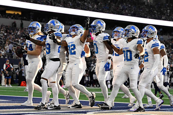 Brian Branch (32) van Detroit Lions viert feest met teamgenoten nadat Branch een pass onderschepte die werd gegooid door Dallas Cowboys quarterback Dak Prescott (4) in de tweede helft van een NFL-voetbalwedstrijd in Arlington, Texas, zondag 13 oktober 2024. (AP Foto/Jerome Miron)