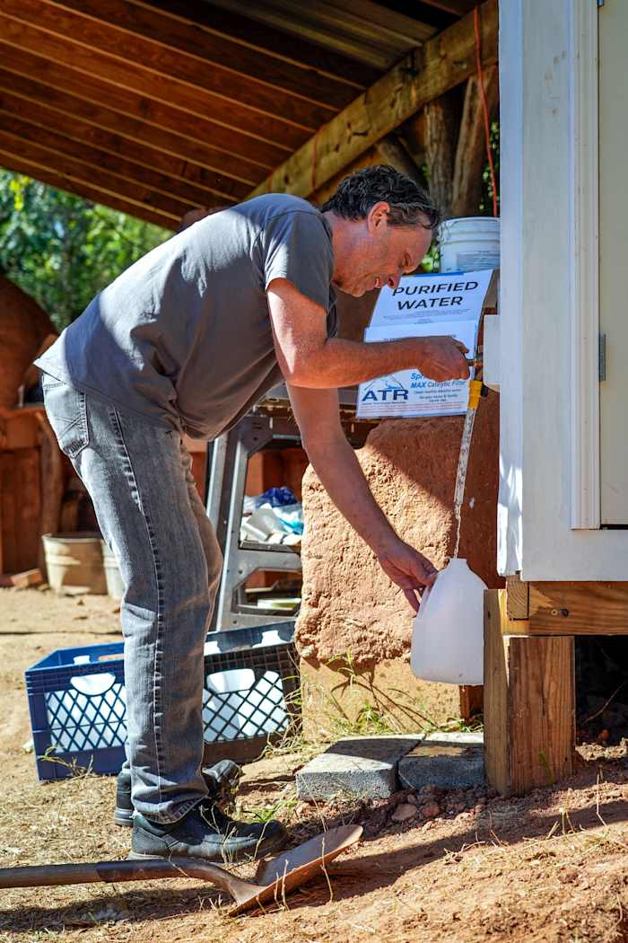 Buurtbewoner Noah Bell haalt gezuiverd water uit een gemeenschap die goed gelegen is op een stadsboerderij die toebehoort aan Bountiful Cities, een non-profitorganisatie, maandag 14 oktober 2024, in Asheville, NC (AP Photo/Kathy Kmonicek)