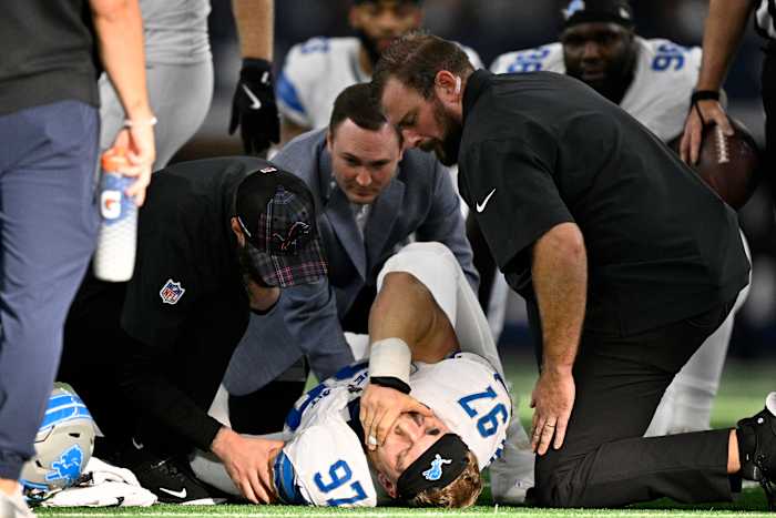 Detroit Lions-defensive end Aidan Hutchinson (97) wordt verzorgd door teampersoneel na een onbekende blessure in de tweede helft van een NFL-voetbalwedstrijd tegen de Dallas Cowboys in Arlington, Texas, zondag 13 oktober 2024. (AP Photo/Jerome Miron )
