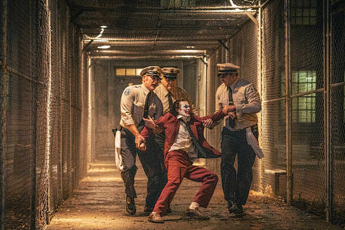 Deze afbeelding vrijgegeven door Warner Bros. Pictures toont Joaquin Phoenix, midden op de voorgrond, en Brendan Gleeson, midden op de achtergrond, in een scène uit "Joker: Folie Deux." (Niko Tavernise/Warner Bros. Afbeeldingen via AP)