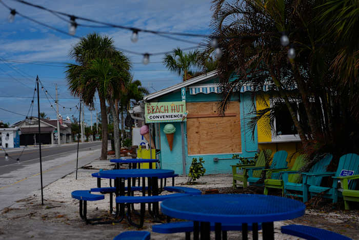 Een dichtgetimmerd bedrijf staat naast een verlaten straat in een evacuatiezone, vóór de aankomst van de orkaan Milton, in Anna Maria, Florida, op Anna Maria Island, dinsdag 8 oktober 2024. (AP Photo/Rebecca Blackwell)