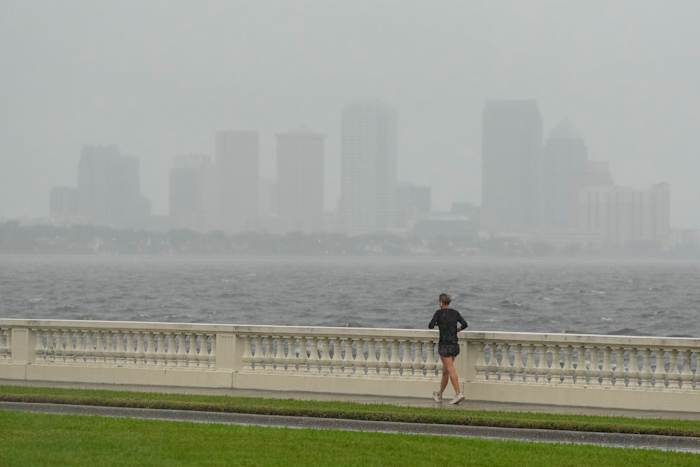 Een jogger draaft in lichte regen voorafgaand aan de aankomst van orkaan Milton, woensdag 9 oktober 2024, in Tampa, Florida. (AP Photo/Julio Cortez)