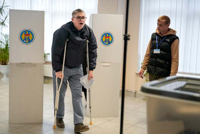 Een man met krukken verlaat op zondag 20 oktober 2024 een stemhokje in Chisinau, Moldavië, tijdens presidentsverkiezingen en een referendum over de vraag of de weg van het land naar het lidmaatschap van de Europese Unie in de grondwet moet worden vastgelegd. (AP Foto/Vadim Ghirda)