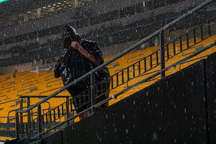 Een toeschouwer staat onder de driving range tijdens een weervertraging voorafgaand aan een NFL-voetbalwedstrijd tussen de Pittsburgh Steelers en de Dallas Cowboys, zondag 6 oktober 2024, in Pittsburgh. (AP Foto/Matt Freed)