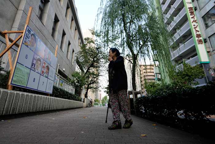 Een vrouw kijkt naar een reclamebord met posters voor kandidatencampagne voor de verkiezingen voor het Japanse lagerhuis, geïnstalleerd in een stembureau in Tokio, Japan, zondag 27 oktober 2024. (AP Photo/Hiro Komae)