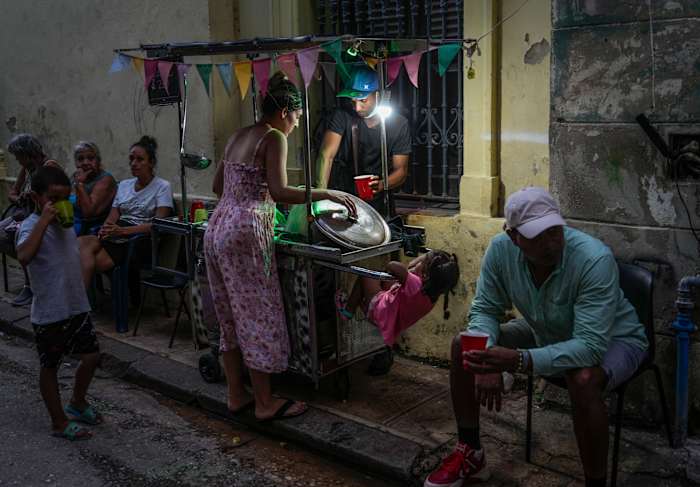 Een vrouw koopt soep van een straatverkoper tijdens een stroomstoring in Havana, maandag 21 oktober 2024. (AP Photo/Ramon Espinosa)