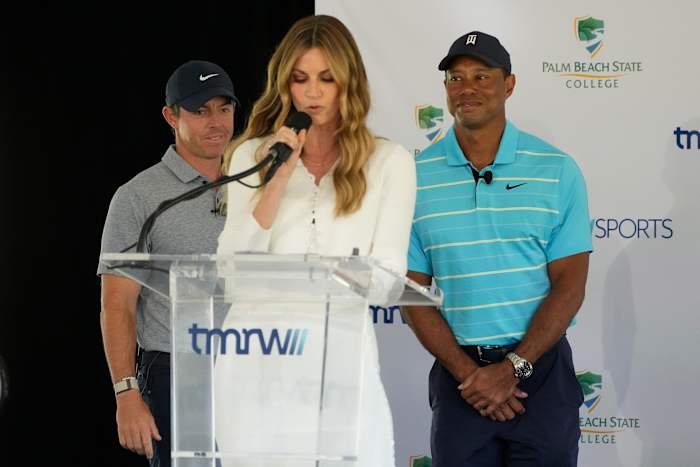 Gastheer Erin Andrews, midden, introduceert golfers Tiger Woods (rechts) en Rory McIlroy tijdens een persconferentie waarin de toekomstige thuisbasis van TGL wordt aangekondigd, een nieuwe met technologie doordrenkte teamgolfcompetitie, dinsdag 21 februari 2023, op de campus van Palm Beach State College in Palm Beach Gardens, Florida. (AP Photo/Wilfredo Lee)