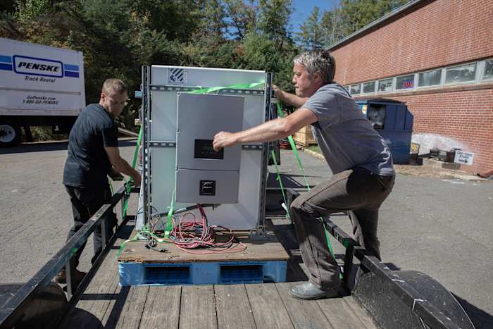 Henry Kovacs, links, en Hayden Wilson, rechts, vrijwilligers bij het Footprint Project, laden twee Tesla Powerwall-batterijen om te leveren aan gemeenschappen die getroffen zijn door de orkaan Helene in Mars Hill, NC op 9 oktober 2024. (AP Photo/Gabriela Aoun Angueria)