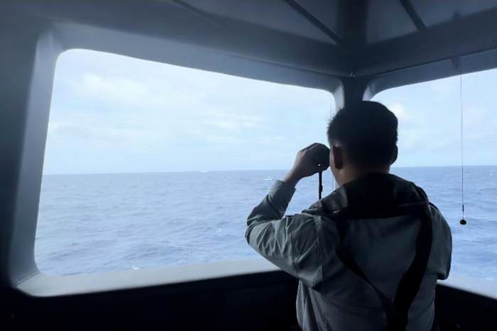 In deze ongedateerde uitgave van de Indonesian Maritime Security Agency (BAKAMLA) gebruikt een Maritime Security Agency een verrekijker om de beweging van een Chinees kustwachtschip in het water van de Noord-Natuna Zee in het betwiste gebied van de Zuid-Chinese Zee, Indonesië, te volgen. , 24 oktober 2024. (BAKAMLA via AP)