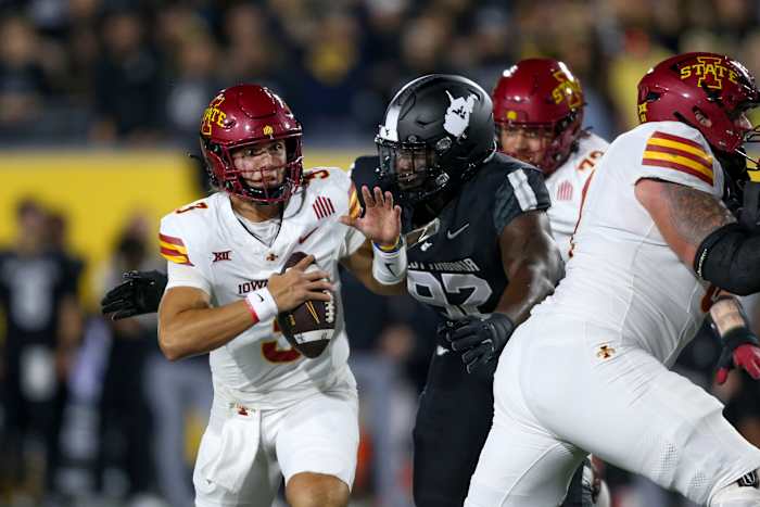 Iowa State quarterback Rocco Becht (3) wordt ontslagen door verdedigingslijnwachter Asani Redwood (92) uit West Virginia tijdens de eerste helft van een NCAA universiteitsvoetbalwedstrijd, zaterdag 12 oktober 2024, in Morgantown, W.Va. (AP Photo/ William Wotring)