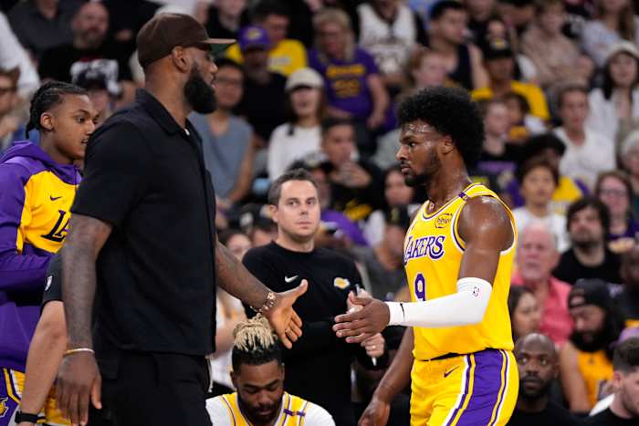 LeBron James uit Los Angeles Lakers, links, begroet zijn zoon, Bronny James terwijl Bronny het veld verlaat tijdens de eerste helft van een NBA-basketbalwedstrijd in het voorseizoen, vrijdag 4 oktober 2024, in Palm Desert, Californië. (AP Photo/ Mark J. Terrill)