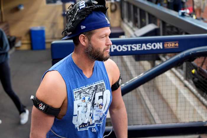 Los Angeles Dodgers-werper Clayton Kershaw draagt ​​een handschoen op zijn hoofd en apparaten op zijn armen in de dug-out tijdens de training op maandag 7 oktober 2024, een dag voor Game 3 van een honkbal NL Division Series tegen de San Diego Padres in San Diego. (AP-foto/Gregory Bull)