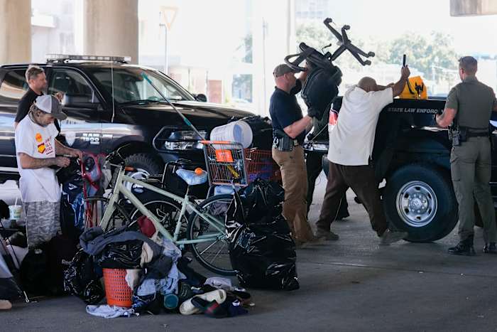 Louisiana Wildlife and Fisheries-agenten helpen de staatspolitie bij het geven van instructies aan mensen die in een daklozenkamp wonen om naar een andere vooraf aangewezen locatie te verhuizen terwijl ze een inspectie uitvoeren voorafgaand aan een Taylor Swift-concert in New Orleans, woensdag 23 oktober. 2024. (AP-foto/Gerald Herbert)