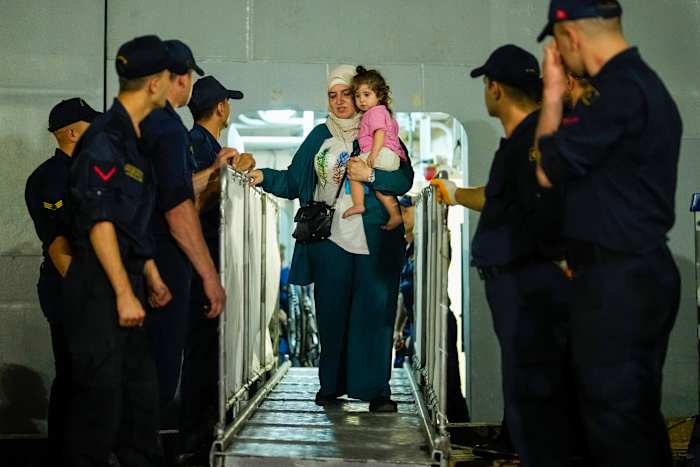 Mensen, voornamelijk Turkse staatsburgers, stappen vroeg op vrijdag 11 oktober 2024 van het Turkse militaire schip TCG Sancaktar nadat ze vanuit de Libanese hoofdstad Beiroet naar Turkije zijn geëvacueerd, in de haven van Mersin, Zuid-Turkije. (AP Photo/Emrah Gurel)