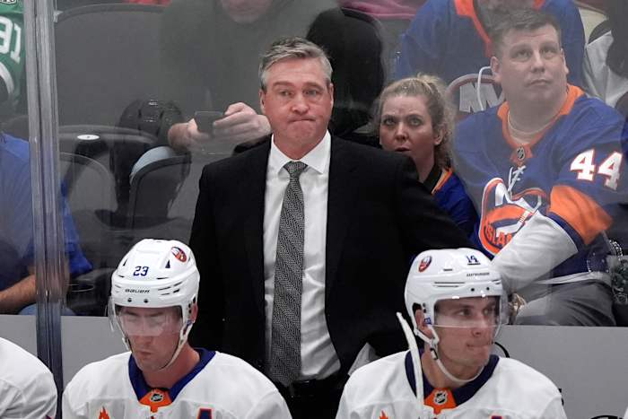 New York Islanders-hoofdcoach Patrick Roy, midden, kijkt van achter de middens Brock Nelson (29) en Bo Horvat (14) toe tijdens de tweede periode van een NHL-hockeywedstrijd tegen de Dallas Stars op zaterdag 12 oktober 2024 in Dallas. (AP Foto/LM Otero)