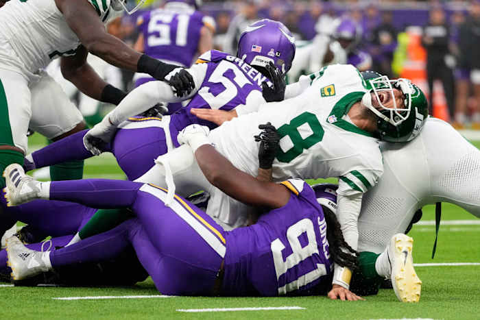 New York Jets quarterback Aaron Rodgers (8), rechts, reageert terwijl hij wordt aangepakt tijdens de tweede helft van een NFL-voetbalwedstrijd tegen de Minnesota Vikings, zondag 6 oktober 2024, in het Tottenham Hotspur-stadion in Londen. (AP-foto/Kirsty Wigglesworth)