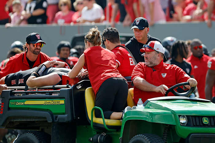 North Carolina State-hoofdcoach Dave Doeren, rechts achter, controleert quarterback Grayson McCall (2) terwijl hij van het veld wordt afgevoerd na een blessure tijdens de eerste helft van een NCAA college football-wedstrijd in Raleigh, NC, zaterdag 5 oktober. 2024. (AP-foto/Karl B DeBlaker)