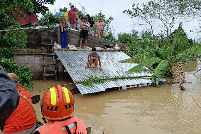 Op deze foto van de Filippijnse kustwacht wachten bewoners die op hun dak blijven om overstromingen veroorzaakt door de tropische storm Trami, plaatselijk Kristine genaamd, te voorkomen op redding in Libon, provincie Albay, Filipijnen op woensdag 23 oktober 2024. ( Filippijnse kustwacht via AP)