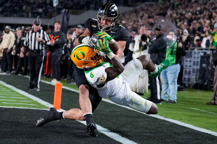 Oregon running back Noah Whittington (6) wordt buiten de baan gedwongen door Purdue linebacker Yanni Karlaftis, top, na het scoren van een touchdown tijdens de tweede helft van een NCAA college football-wedstrijd in West Lafayette, Ind., vrijdag 18 oktober 2024 (AP-foto/AJ-mast)