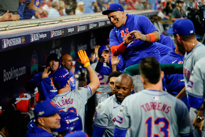 Pete Alonso van New York Mets, linksonder, geeft een high five aan een teamgenoot na het slaan van een RBI-opofferingsslag tijdens de achtste inning van Game 1 van een honkbal NL Division Series tegen de Philadelphia Phillies, zaterdag 5 oktober 2024, in Philadelphia. (AP-foto/Chris Szagola)