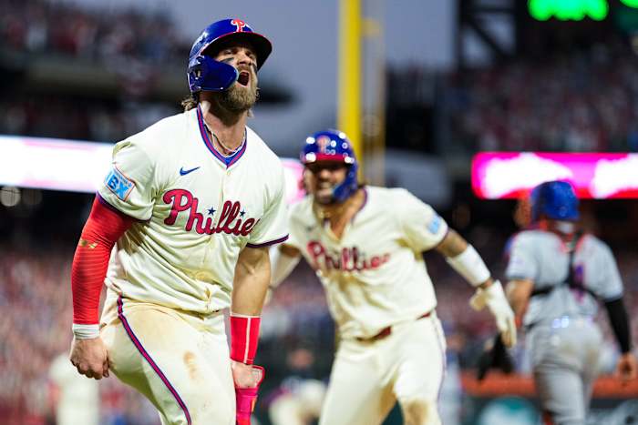 Philadelphia Phillies' Bryce Harper, links, en Nick Castellanos vieren feest na het scoren op een twee-run triple hit van Bryson Stott tijdens de achtste inning van Game 2 van een honkbal NL Division Series tegen de New York Mets, zondag 6 oktober 2024, in Philadelphia. (AP Foto/Matt Slocum)