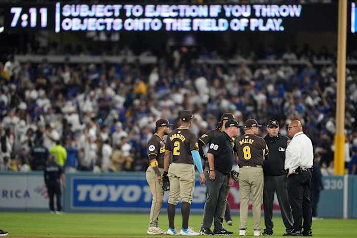 San Diego Padres-manager Mike Shildt (8) en spelers praten met scheidsrechters nadat er items op het veld waren gegooid door fans tijdens de zevende inning in Game 2 van een honkbal NL Division Series tegen de Los Angeles Dodgers, zondag 6 oktober 2024, in Los Angeles. (AP-foto/Ashley Landis)