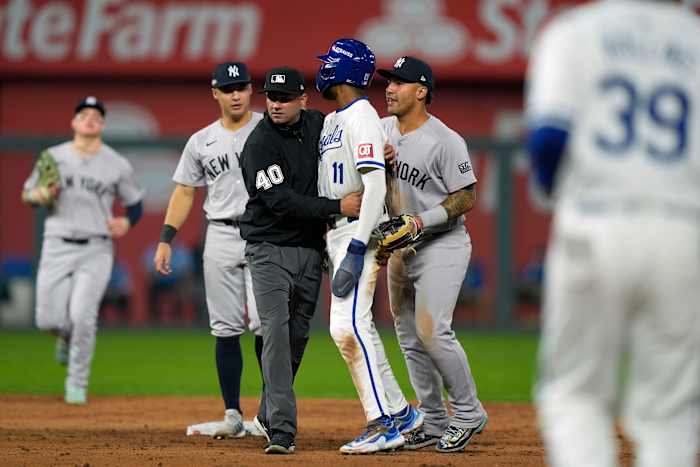 Scheidsrechter Roberto Ortiz houdt Maikel Garcia (11) van Kansas City Royals tegen nadat hij is uitgetikt door New York Yankees korte stop Anthony Volpe toen de banken leeg waren na een dubbelspel tijdens de zesde inning in Game 4 van een honkbal-playoff-serie van de American League Division donderdag, 10 oktober 2024, in Kansas City, Missouri (AP Photo/Charlie Riedel)