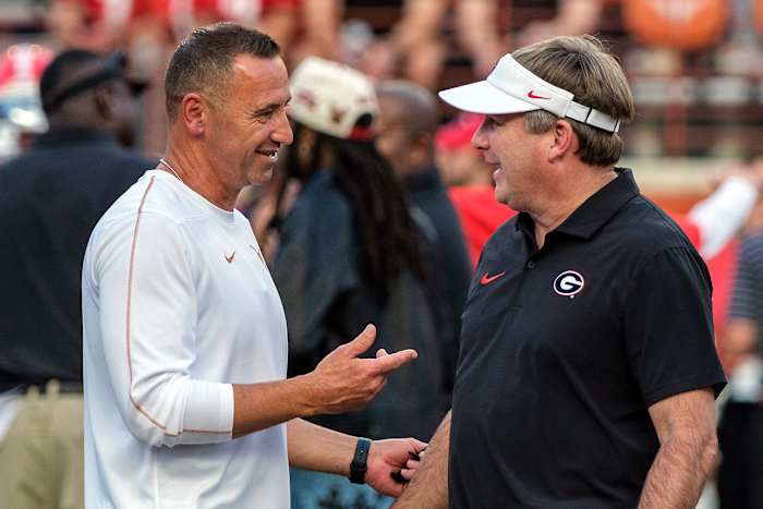 Texas-hoofdcoach Steve Sarkisian, links, en Georgia-hoofdcoach Kirby Smart praten tijdens de pregame van een NCAA universiteitsvoetbalwedstrijd in Austin, Texas, zaterdag 19 oktober 2024. (AP Photo/Rodolfo Gonzalez)