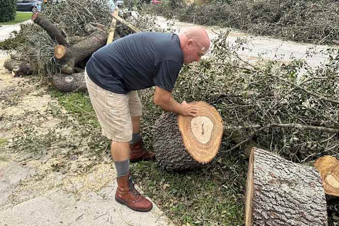 Tony Brazzale verwijdert een deel van een boom die door een tornado is geveld voor zijn huis in Wellington, Florida, vrijdag 11 oktober 2024. (AP Photo/Stephany Matat)
