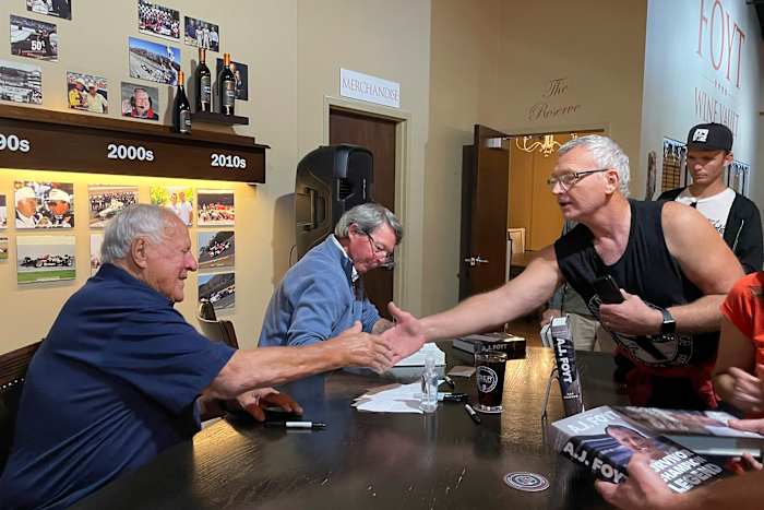 Viervoudig Indianapolis 500-winnaar AJ Foyt, links, schudt een fan de hand tijdens een signeersessie, donderdagavond 10 oktober 2024, in de Foyt Wine Vault in Speedway, Ind. Foyt en auteur Art Garner, middenachter, waren in de stad om de release van Garners nieuwe biografie te promoten "AJ Foyt - Deel 1: Overlevende, kampioen, legende." Een tweede deel heeft een voorlopige releasedatum van mei 2026. (AP Photo/Michael Marot)