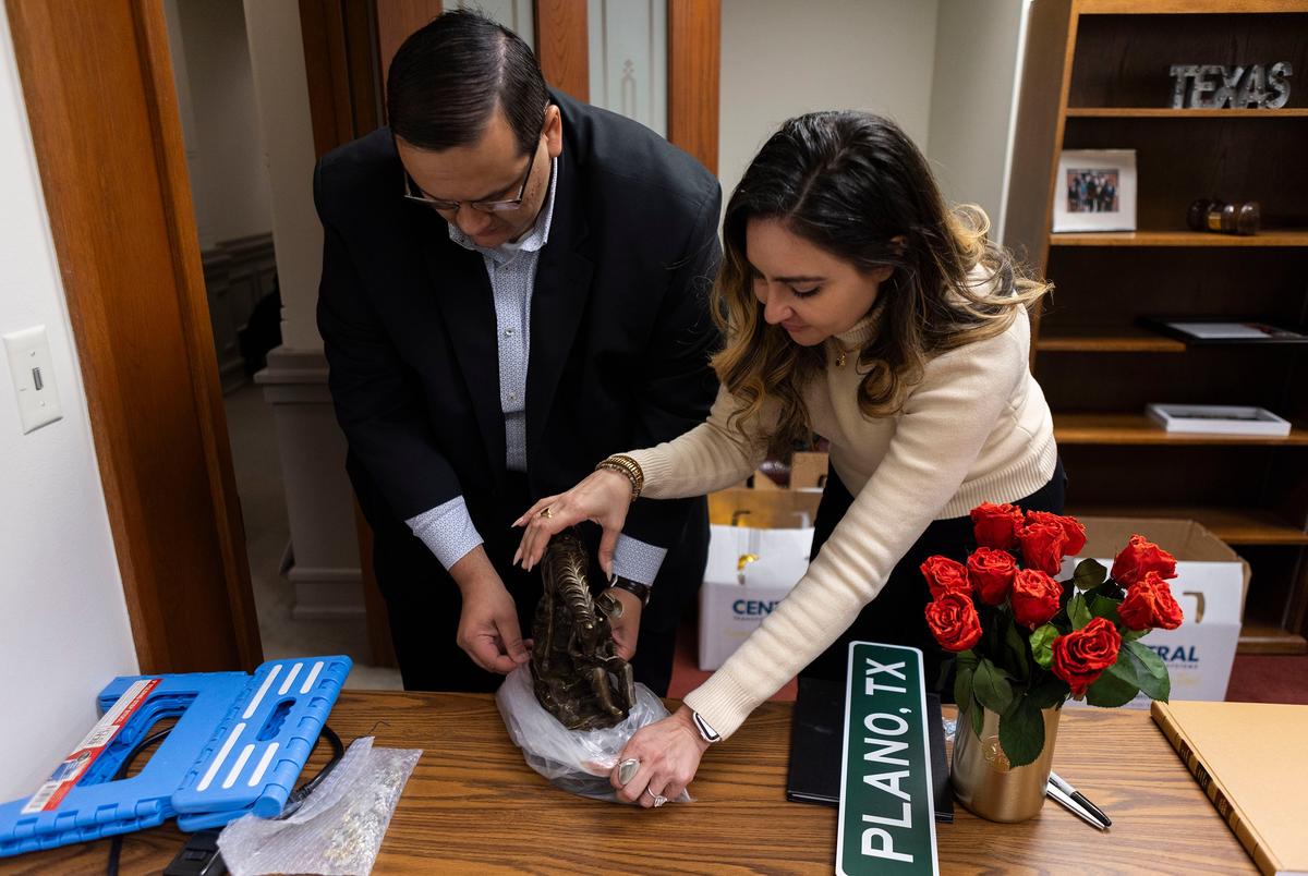 Stafchef Jordan Villarreal en vertegenwoordiger Mihaela Plesa (D-Dallas) pakken haar Remington-beeld uit terwijl ze op 12 december 2024 haar nieuwe kantoor in het Texas State Capitol betrekken. Het standbeeld, een cowboy die een boek leest, werd geschonken aan haar door de ambassadeur van Roemenië.