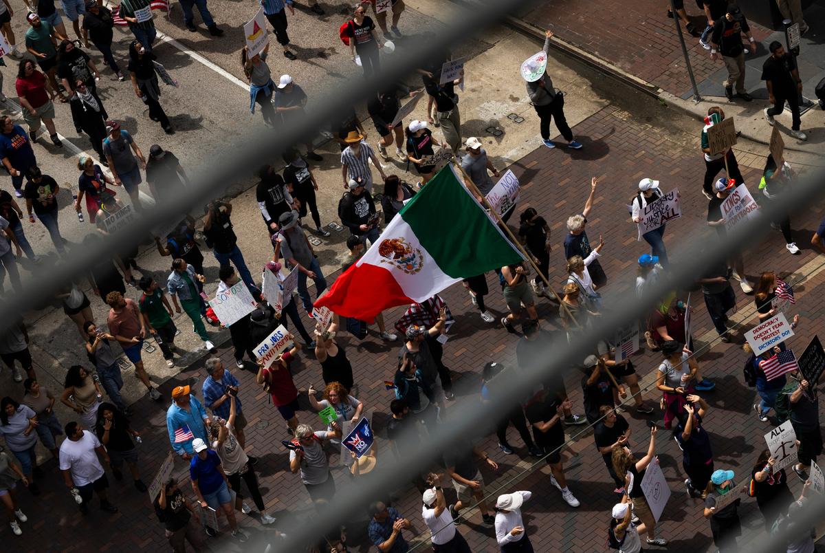 Een demonstrant draagt de Mexicaanse vlag terwijl mensen Walker Street op marcheren tijdens een No Kings -protest in het stadhuis, zaterdag 14 juni 2025 in Houston. (Antranik Tavitian voor de Texas Tribune)
