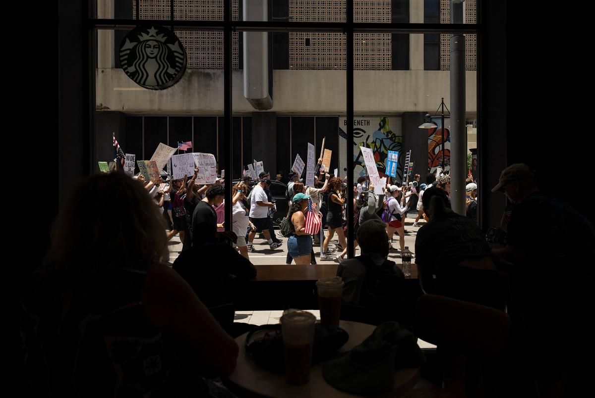 Mensen kijken naar de No Kings Protest van een Starbucks op zaterdag 14 juni 2025 in Dallas, Texas. De No Kings Day of Defiance werd naar verwachting de grootste mobilisatie van één dag sinds Trump terugkeerde naar kantoor.