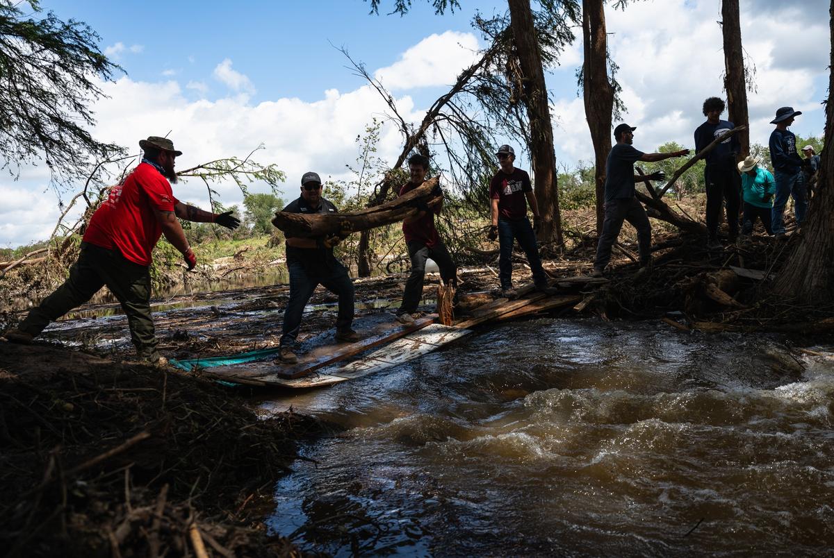 Vrijwilligers vormen een emmerbrigade om overstromingsafval te verplaatsen van een stapel gevormd in een deel van de Guadalupe -rivier, terwijl ze helpen bij herstelinspanningen in Camp Camp, een zomerkamp voor mensen met een handicap georganiseerd door Children's Association for Maximum Potential, vrijdag 11 juli 2025, in Center Point.