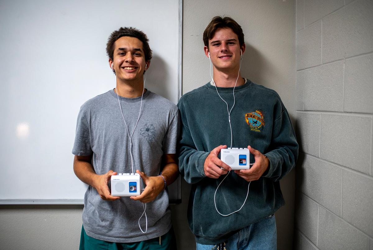 Senioren Jonah Farrington en Tripp Henderson tonen hun cassettebandspelers op Lago Vista High School op dinsdag 9 september 2025 in Lago Vista, TX. Na het overlijden van HB 1481 Lago Vista heeft een beleid geïmplementeerd waarbij studenten apparaten opbergen, voornamelijk mobiele telefoons, in magnetisch vergrendelde zakjes die ook de mobiele telefoonservice blokkeren, kunnen de apparaten worden ontgrendeld in het geval van een noodgeval en wanneer de studenten het gebouw verlaten met een wandgemonteerde sleutel in de buurt van de ingang van het gebouw. Vanwege het nieuwe beleid zijn sommige studenten begonnen met het binnenhalen van muziekspelers zoals bandspelers of mp3 -spelers om nog steeds van muziek te kunnen genieten terwijl ze op school zijn. (Sergio Flores voor de Texas Tribune)