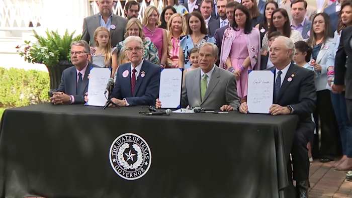 Regering Greg Abbott tekent Camp Safety Bills in de wet, omringd door Camp Mystic Families